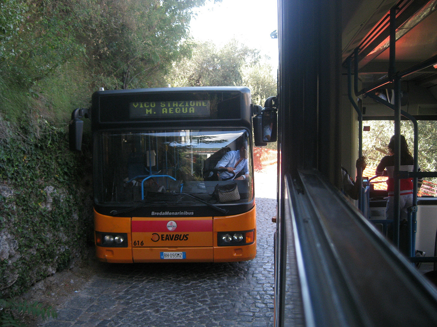 Twee bussen passeren elkaar op smalle weg., Two busses passing on a narrow road.